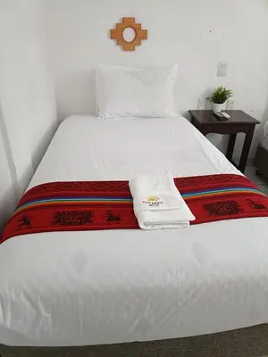 a white bed with two towels on top of it at PAKARINA HOTEL in Machu Picchu