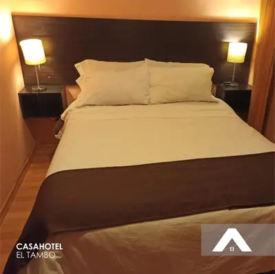 a bed in a hotel room with two lamps at CasaHotel El Tambo Huancayo in Huancayo