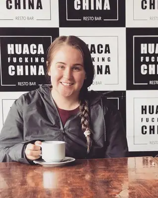 a woman sitting at a table with a cup of coffee at Hotel Sand and Lake in Ica