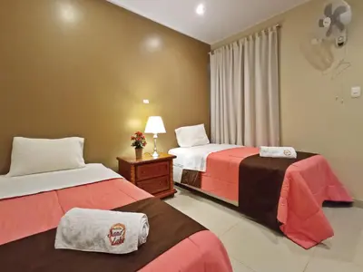 a hotel room with two beds and a lamp at Hotel Sand and Lake in Ica