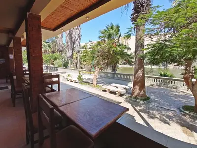 a table on the porch of a restaurant with trees at Hotel Sand and Lake in Ica