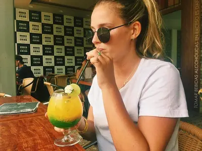 a woman sitting at a table with a drink at Hotel Sand and Lake in Ica