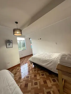 a bedroom with two beds and a wooden floor at Vertigo Climbing Hostel in Urubamba