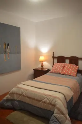 a bedroom with a bed with a lamp and a painting at ROOM Lima House centro in Lima