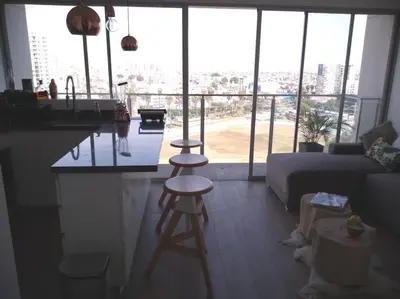 a kitchen with a counter and stools in a living room at Barranco landscape suite boardwalk in Lima