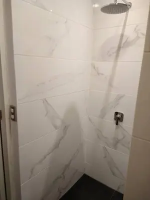 a bathroom with a shower with white marble walls at Barranco landscape suite boardwalk in Lima