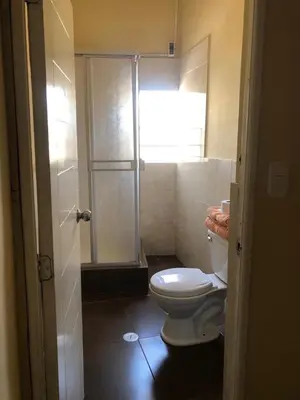 a bathroom with a toilet and a glass shower at Hostal Huacachina Sunset in Ica