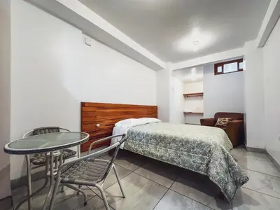 a bedroom with a bed and a table and chair at Excelente ubicación! Bellas y cómodas habitaciones en el centro de Oxapampa in Oxapampa