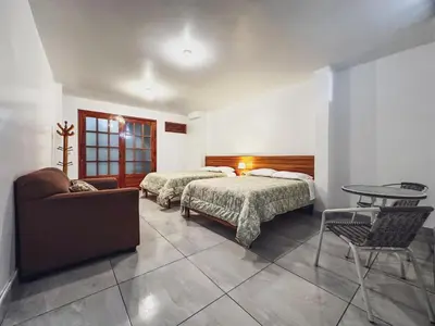 a bedroom with two beds and a table and a couch at Excelente ubicación! Bellas y cómodas habitaciones en el centro de Oxapampa in Oxapampa