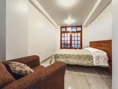 a bedroom with a bed and a couch at Excelente ubicación! Bellas y cómodas habitaciones en el centro de Oxapampa in Oxapampa