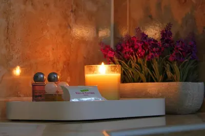 a candle and a vase with flowers on a table at Hotel Villa de Valverde in Ica