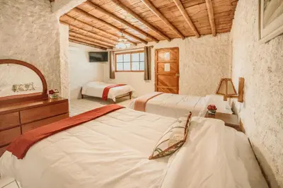 a bedroom with two beds and a dresser and a mirror at Hotel Fundo El Arrabal in Ica