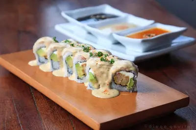 a wooden cutting board with sushi and a plate of soup at Hotel El Huarango in Ica