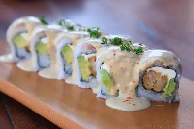 a row of sushi on a wooden cutting board at Hotel El Huarango in Ica