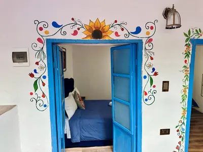 a bedroom with a blue door with a sunflower on the wall at AITANA'S HOUSE - SAN BLAs in Cusco
