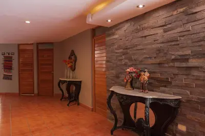 a hallway with a stone wall and a table with figurines on it at Hotel El Huacachinero- Hotel Familiar in Ica