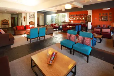 a living room with blue chairs and a bar at San Agustin Plaza in Cusco