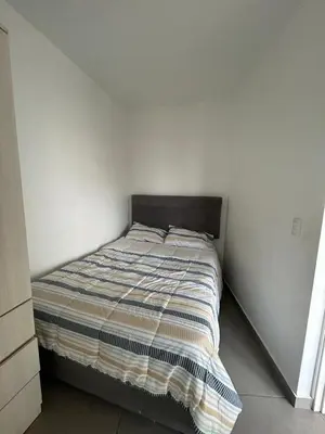 a bed in a room with a white wall at Departamento de Playa (con piscina propia) en km 107 Asia, Lima in Asia