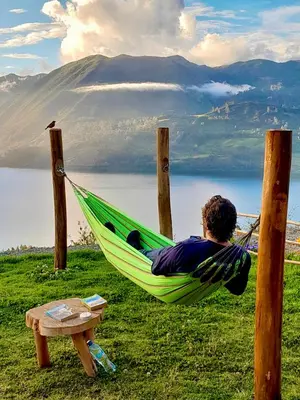a man laying in a hammock overlooking a lake at Pacucha Glamping in Andahuaylas