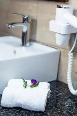 a white towel with a flower on it next to a sink at Rockrivers Plaza MachuPicchu in Machu Picchu