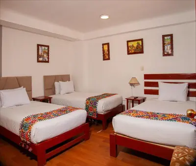 a hotel room with two beds and two tables at Hotel Valle Mistico in Ollantaytambo