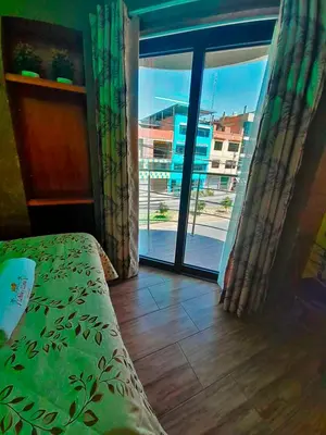 a room with a bed and a sliding glass door at HOTEL LA BELLA Y EL LEON in Huánuco