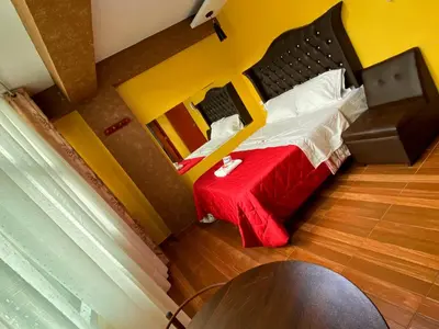 a small bedroom with a bed with a red blanket at HOTEL LA BELLA Y EL LEON in Huánuco