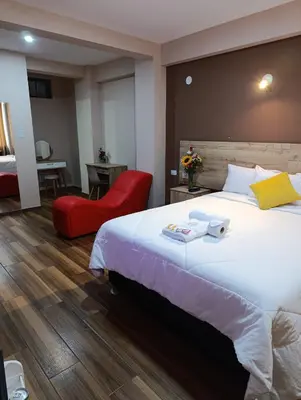 a hotel room with a large bed and a red chair at Arabian Hotel in Lima
