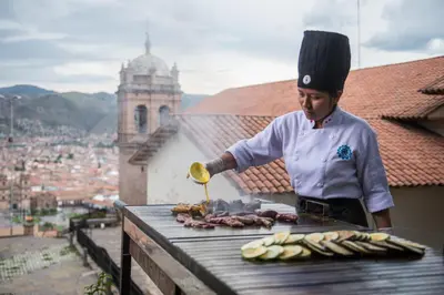 a man cooking food on a grill on a table at Palacio Manco Capac by Ananay Hotels in Cusco