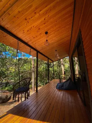 a wooden porch with a swing and a chair at Oasis Blue Oxapampa in Palmira