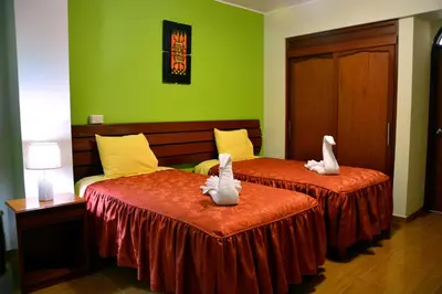 two white swans sitting on two beds in a room at Hotel Sol del Sur in Nazca