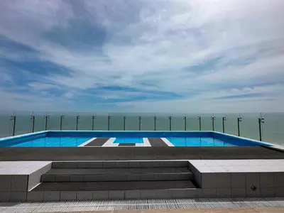a swimming pool with stairs and the ocean in the background at Departamento con vista al mar y piscina - Pool One in Lima