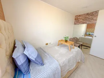 a bedroom with a bed with blue pillows and a table at Departamento con vista al mar y piscina - Pool One in Lima