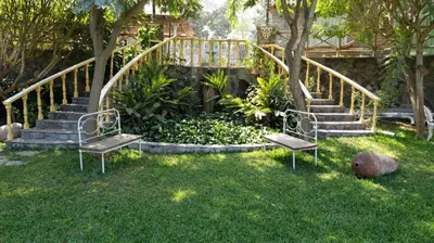 two benches sitting in the grass next to a staircase at Hacienda Santa María de Cieneguilla in Cieneguilla