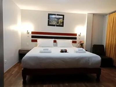a bedroom with a large white bed and a chair at Raymi MachuPicchu in Machu Picchu