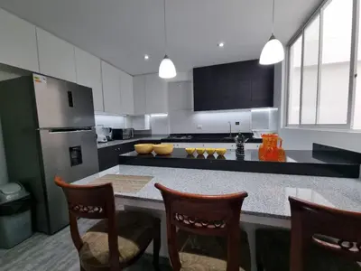 a kitchen with a counter with chairs and a refrigerator at Departamento estreno 2do piso in La Molina