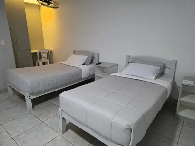 two beds in a room with two tables and a chair at Hotel Real San Pedro in El Puente
