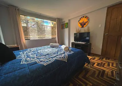 a bedroom with a blue bed and a television at Kintu Apartamento cusco in Cusco