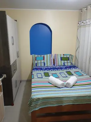 a bed with a blue headboard and two pillows on it at Mi hermosa Casita con baño y cocina privados in Lima