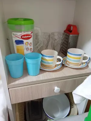 a shelf with cups and plates and a blender at Mi hermosa Casita con baño y cocina privados in Lima