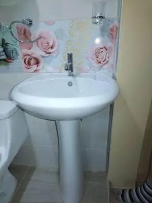a white sink in a bathroom with a picture of roses at Mi hermosa Casita con baño y cocina privados in Lima
