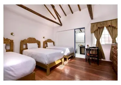a bedroom with two beds and a table and a mirror at Inkarri Regocijo Plaza in Cusco