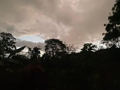 a cloudy sky with trees in the foreground at Carol Haus in Oxapampa