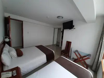 a hotel room with a bed and a television at Flower's House MachuPicchu in Machu Picchu