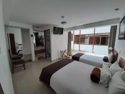 a hotel room with two beds and a large window at Flower's House MachuPicchu in Machu Picchu