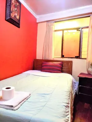 a bed in a room with red walls and a window at Hospedaje Apu Salka in Cusco