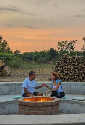 a man and woman sitting in front of a fire pit at Viñedo Sotelo - Hospedaje y Glamping in San Juan Bautista
