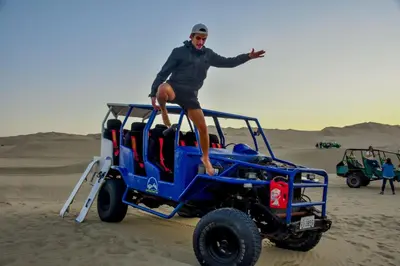 a man standing on the back of a jeep in the desert at HAWKA in Ica