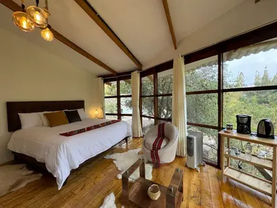 a bedroom with a bed and large windows at Spirit Of The River Lodge in Cusco