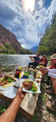 a group of people sitting at a table with plates of food at Spirit Of The River Lodge in Cusco